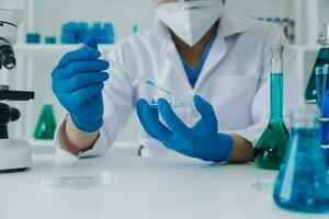 hand av forskare med testa rör och flaska i medicinsk kemi labb blå baner bakgrund foto