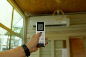 mobil avlägsen kontrollera justerar de temperatur av de luft balsam i de hus till 25 grader celsius till spara elektricitet. mjuk och selektiv fokus. foto