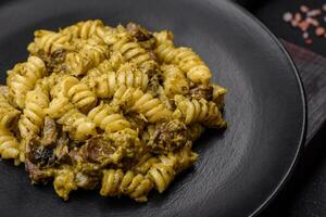 utsökt fusilli pasta med grön pesto sås, med salt och kryddor foto