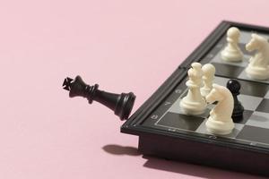 schackmatta med svart kung på rosa bakgrund foto