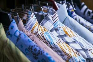 färgrik mängd av shirts hängningar i en Kläder showroom. kluster fokus foto