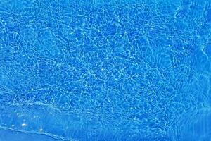 blå vatten med krusningar på de yta. defokusering suddig transparent blå färgad klar lugna vatten yta textur med stänk och bubblor. vatten vågor med lysande mönster textur bakgrund. foto