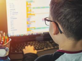 smart ung pojke arbetar på en dator för sitt nya projekt i sin datavetenskapsklass