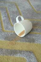 kopp av kaffe spillts på grå Färg golv matta foto