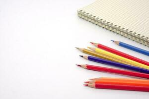 fokus av färgad pennor eller pastell fodrad upp och fläck Graf bok på vit bakgrund. inlärning, studie och presentation begrepp. foto