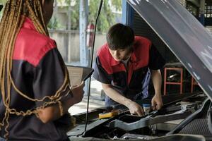 två professionell bil- mekanisk partners kolla upp och reparera ett ev bil batteri och hybrid motor på en underhåll garage, expert- elektrisk fordon service, och fixering yrken bil industri. foto