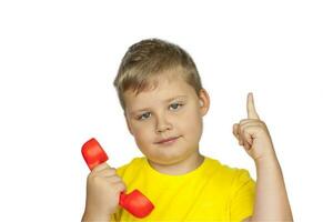 en pojke i en gul t-shirt på en vit bakgrund med en röd telefon mottagare. pekar på till ring upp här. de begrepp av en baner med information. Plats för de text. foto