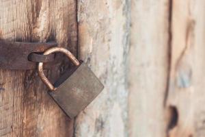det gamla och vintage metallhänglåset med rost på trädörren låst för säkerhet foto