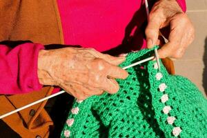 gammal kvinna med stickning nålar och ull foto