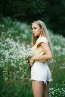 en flicka i en fält med blommor. skön ung kvinna i en fält med vit äng blommor. foto