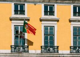 portugisiska flagga på gul Fasad reflekterande på fönster foto