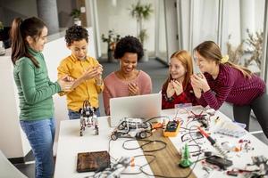 glada barn med sin afroamerikanska kvinnliga naturvetenskapslärare med bärbar dator som programmerar elektriska leksaker och robotar i klassik för robotik