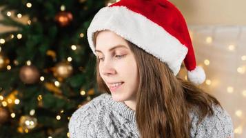 porträtt av en ung kvinna i en grå tröja och jultomtenhatt foto