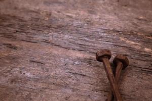 två gamla rostiga naglar vilar på en träbakgrund foto