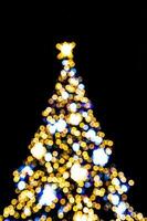 suddig lampor belysande de jul träd på en svart bakgrund foto