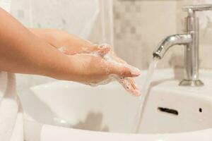 ung kvinna tvättning händer gnuggning med tvål förebyggande för coronavirus, stänga upp foto