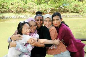 grupp av fem kvinna vänner malaysiska kinesisk indisk asiatisk utomhus- parkera sjö natur kramas omtänksam skrattande Lycklig foto