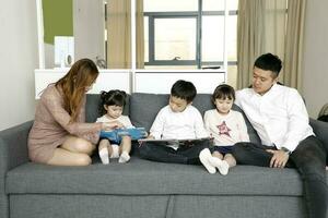 föräldrar barn familj far mor dotter son sitta på soffa läsning skrivning studie undervisning foto