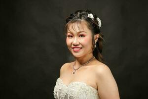 ung asiatisk kvinna i vit klänning hår krona på svart bakgrund foto