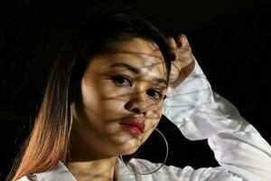 ung skön modern malaysiska kvinna bakgrund med gobo kasta skugga på ansikte foto
