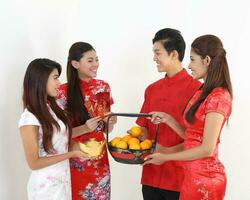 söder öst asiatisk ung malaysiska kinesisk indisk man kvinna bär traditionell kina Cheongsam klänning på vit bakgrund affär utbyta gåva orange hälsningar dela med sig ras- enhet harmoni hand fläkt foto