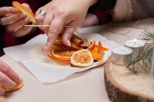 kvinnor hand gör dekorationer från torkade apelsiner