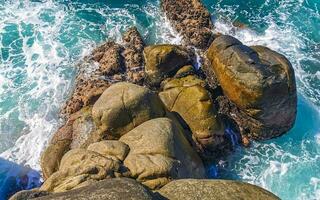 surfare vågor turkos blå vatten stenar klippor stenblock puerto escondido. foto