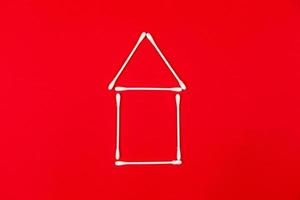 öronpinnar av bomull ordnade som ett litet hus på röd bakgrund foto