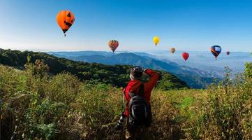 professionell fotograf tar landskapsbilder på ett berg med luftballonger i bakgrunden foto