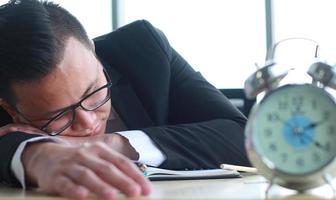 porträtt av ung asiatisk affärsman som sover på skrivbordet i trötthet foto
