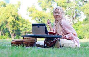 vacker muslimsk flicka sitter lyckligt i parken foto