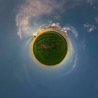 liten planet i blå himmel med vackra moln. transformation av sfäriskt panorama 360 grader. sfärisk abstrakt flygfoto. utrymmets krökning. foto