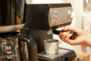 kvinna hand använda sig av en kaffe maskin för koka upp de kaffe och framställning tjäna till deras kund. foto
