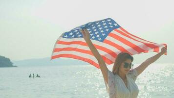 ung kvinnor håll amerikan flaggor på de strand och de hav på deras sommar semester och de leende och njut av deras semester. foto