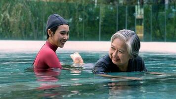 ung tränare portion senior kvinna i aqua aerobics och arbetssätt ut i de slå samman. gammal kvinna och mogna man håller på med aqua aerobics övning i simning slå samman, äldre sporter, och aktiva livsstil begrepp. foto