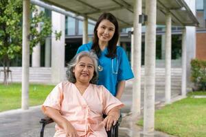 asiatisk omsorgsfull vårdgivare eller sjuksköterska som tar hand om patienten i rullstol. begreppet lycklig pensionering med omsorg från en vårdgivare och besparingar och senior sjukförsäkring, en lycklig familj foto