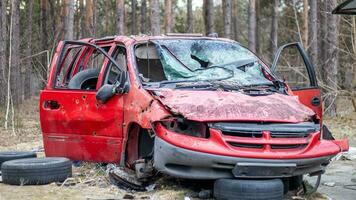 rostig och bruten röd övergiven bil på de stad gata. övergiven gammal bil olycka utomhus. gammal övergiven rostig bil utan hjul på de sida av de väg. foto