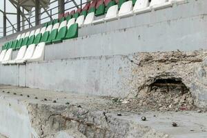 krig i ukraina. exploderad fotboll stadion som en resultat av raket ge sig på. bruten bänkar för fläktar i de står. förstörd står av de stadion. bruten fläkt säten. foto