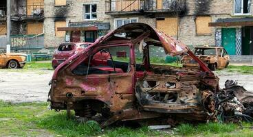 de bil den där bränt ner efter de bombning av de stad står i de gård av en förstörd hus. krig mellan ryssland och ukraina. fragment av en bil efter artilleri beskjutning. foto