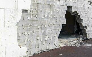 de vägg av en byggnad misshandlade förbi raket fragment i en krig zon. skalade vägg. Fasad av en utbombade byggnad. väpnad konflikt i ukraina. skada till de hus som en resultat av artilleri beskjutning. foto