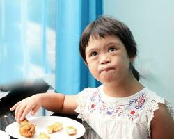 liten söder öst asiatisk flicka äter lunch Sammanträde på dining tabell. hon ha ner syndrom foto