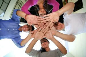 grupp av asiatisk ung man kvinna vän studerande kollegor ser ner händer tillsammans i cirkel foto