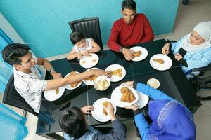 grupp av sydöst asiatisk vuxen barn flicka manlig kvinna äter lunch på dining tabell sparken kyckling. de är autistisk ner syndrom adhd lam rullstol foto