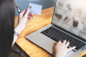 ung kvinna som håller kreditkortet och använder datorn för online-shopping
