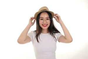 skön ung söder öst asiatisk kvinna bär glasögon gyllene ram glasögon hatt utgör mode stil vit bakgrund se runt om kopia text Plats händer på hatt foto