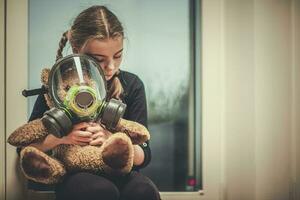 leksak Björn med gas mask omfamnade förbi ung flicka. foto