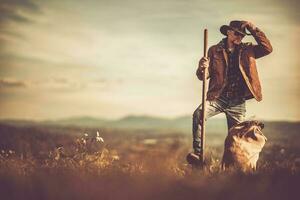 cowboy med en trädgård gaffel i hans hand vistas i främre av hans jordbruksmark foto