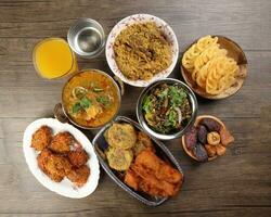 bengali iftar ramadan frukost spridning mogen datum kika friterad kryddad piaju lök montör äggplanta tanpura potatis hacka haleem jilapi khichuri ris chana sola curry på rustik trä- tabell foto