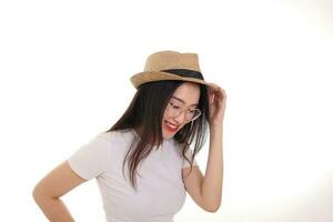 skön ung söder öst asiatisk kvinna bär glasögon gyllene ram glasögon hatt utgör mode stil vit bakgrund hand på hatt huvud foto