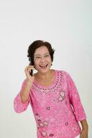 äldre asiatisk kinesisk kvinna på vit bakgrund talande på telefon Lycklig glädje leende foto